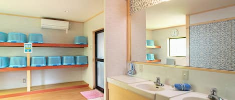 A bathroom with two sinks, a mirror, and shelves with blue baskets.