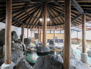 A traditional Japanese onsen with a wooden structure, large rocks, and a hot spring area. - Hotel Hanageshiki (Ukiha)