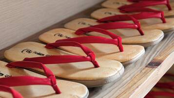 A row of wooden flip-flops with red straps on a shelf.