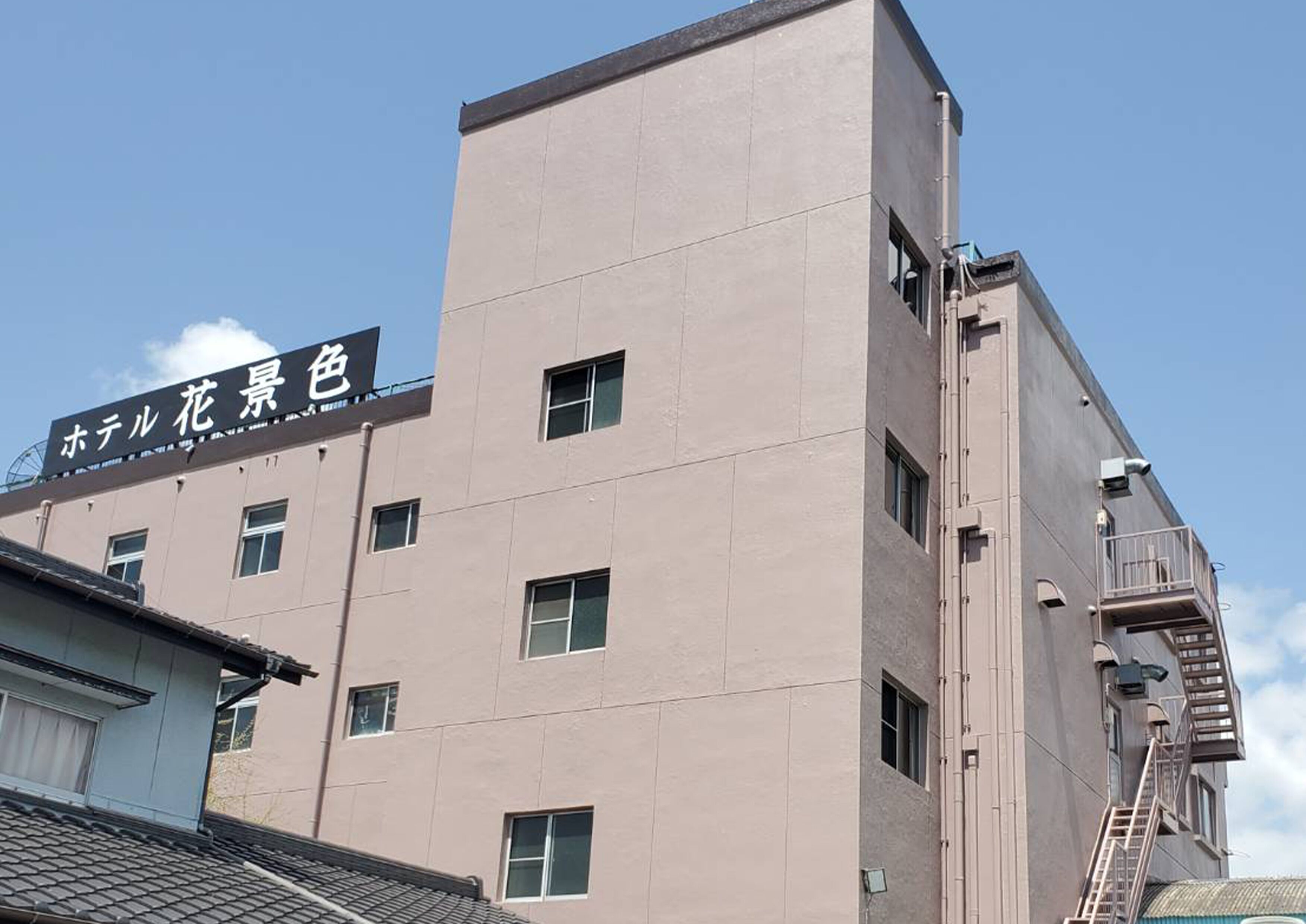 A modern building with a sign reading "Hotel Flower Color" in Japanese.