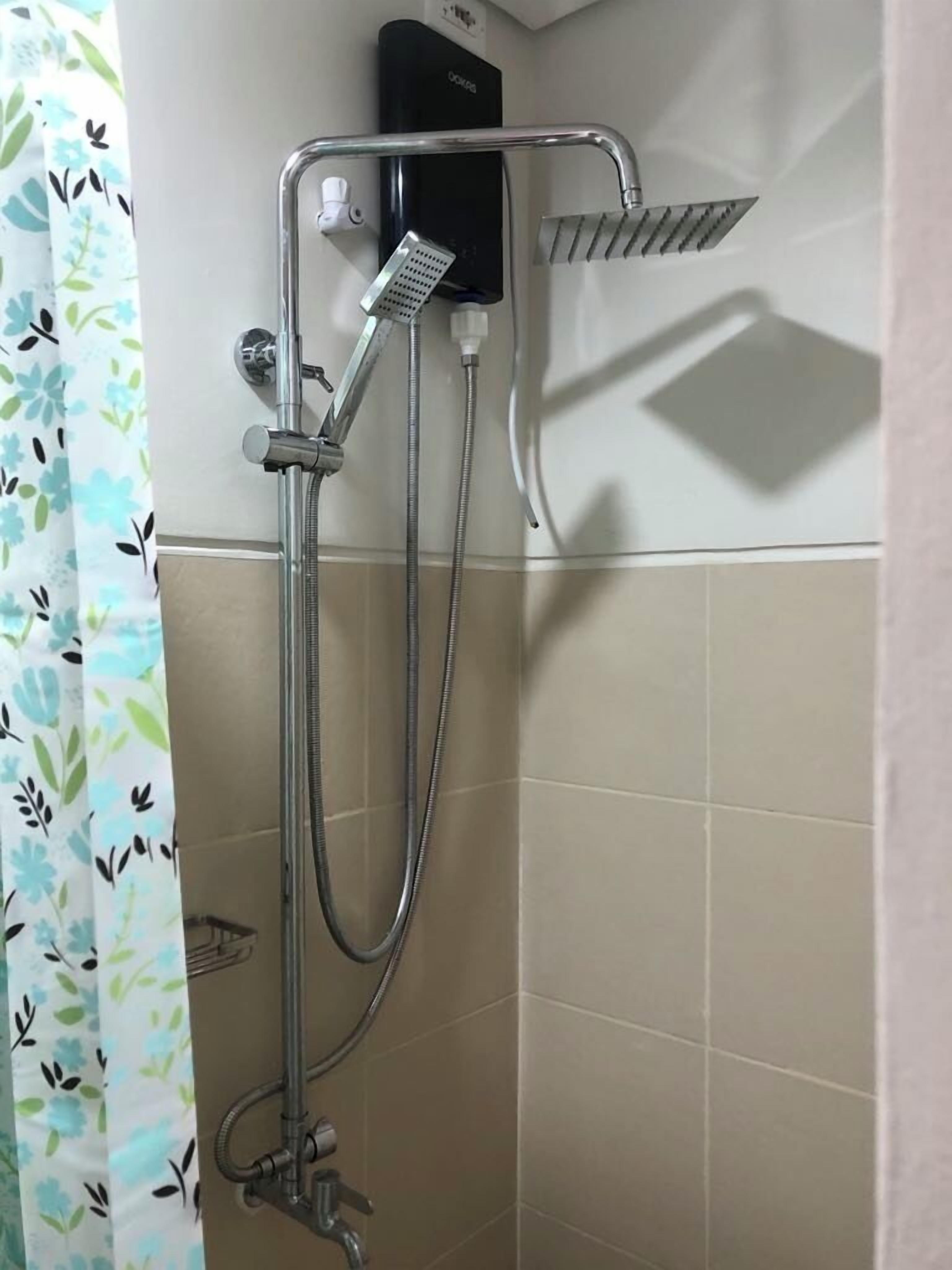A shower with a handheld showerhead, a wall-mounted faucet, and a soap dispenser.