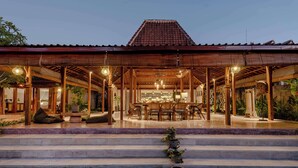 Ein hölzernes Pavillon mit Ziegeldach, ein Essbereich mit Tisch und Stühlen sowie Stufen, die zum Eingang führen.