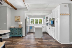 A kitchen with white cabinets, a central island, and a window.