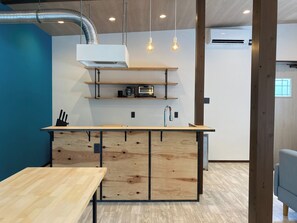 Una cocina moderna con una isla de madera, estantes empotrados e iluminación colgante.