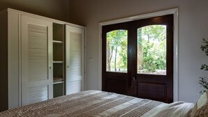 A bedroom with a bed, a wardrobe, and a door leading to a garden. - Charming 2-bedroom Villa (Pares)