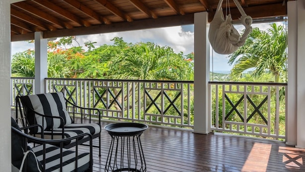 A covered outdoor area with a wooden ceiling, a hanging chair, and a table. - Charming 2-bedroom Villa (Pares)