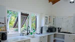 A modern kitchen with white cabinets, a built-in microwave, and a sink. - Charming 2-bedroom Villa (Pares)