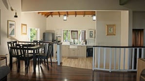 A spacious room with a wooden ceiling, a dining area with a table and chairs, a kitchen with a sink and cabinets, and a view of greenery outside. - Charming 2-bedroom Villa (Pares)