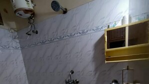 Ein Badezimmer mit Dusche, Toilette und Waschbecken. An der Wand befinden sich ein Handtuchhalter und ein Seifenspender.