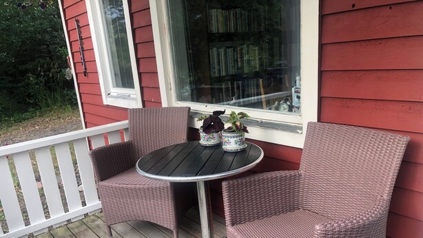 A small outdoor patio with wicker furniture and a table, surrounded by a white railing. - Cozy Cottage in Stockholms Archipelago (Stockholms län)