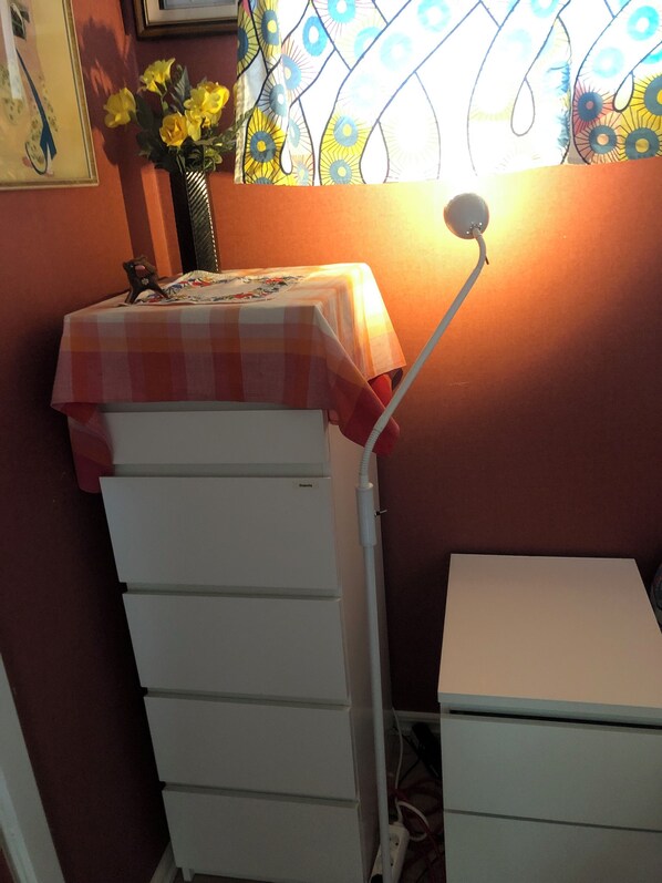 A room with a white cabinet, a small table with a checkered tablecloth, and a vase with yellow flowers. - Cozy Cottage in Stockholms Archipelago (Stockholms län)