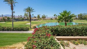 Un campo de golf con un estanque, palmeras y césped bien cuidado.