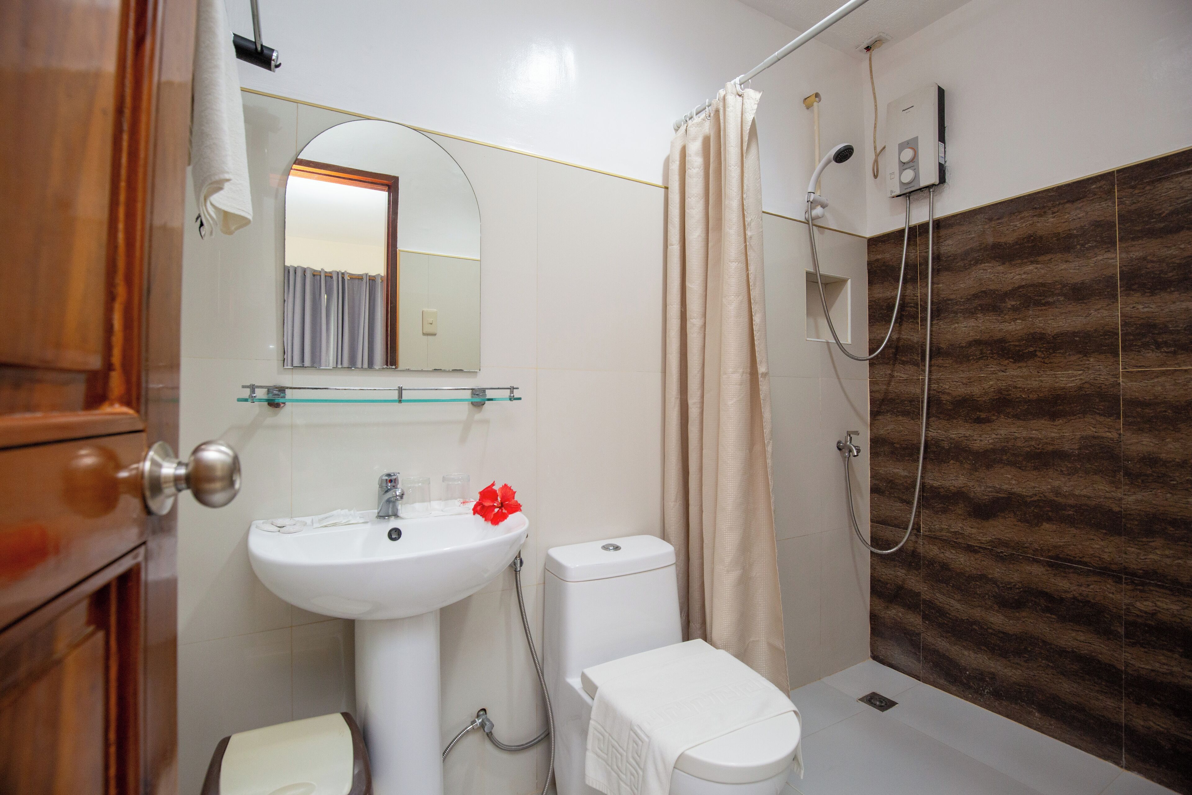 Un baño con lavamanos, inodoro y ducha blancos.