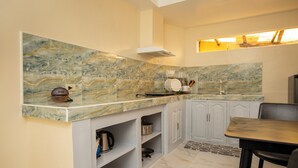 A kitchen with marble countertops, a built-in oven, and a dining area with a table and chairs. - Vilus Place  (Boracay Island)