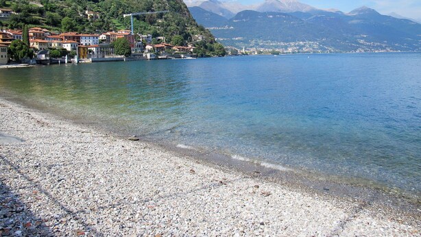 A pebble beach with buildings on a hillside and mountains in the background. - Nice apartment for 4 people with WIFI, TV and patio (Musso)