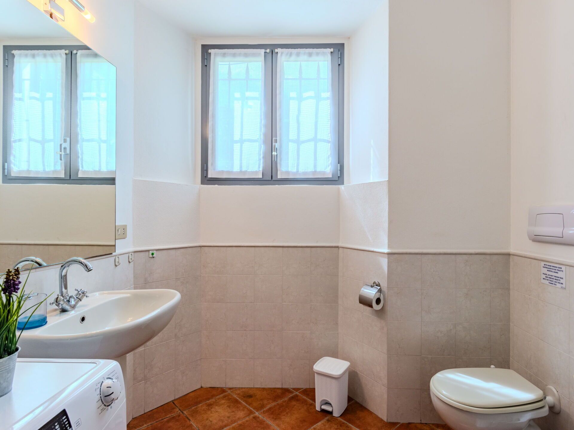 A bathroom with a sink, toilet, and window.