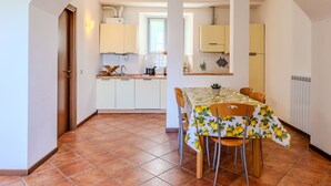 A dining area with a table set for four, a kitchen in the background, and a tiled floor. - Lovely apartment for 4 guests with WIFI, TV and patio (Musso)