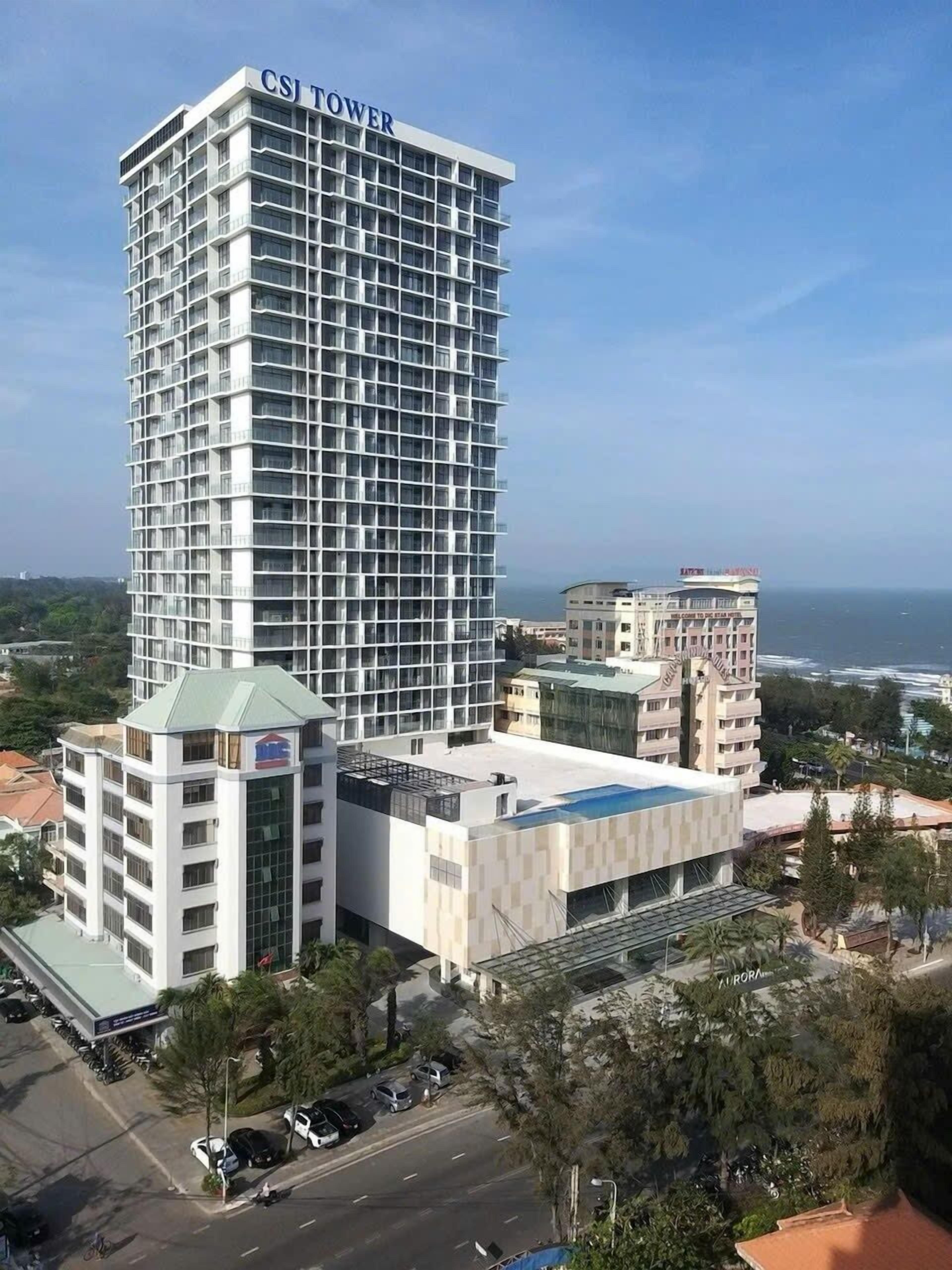 Un grand hôtel moderne appelé « CSI Tower », doté d’une façade à motifs géométriques, entouré d’autres immeubles et offrant une vue dégagée sur la mer.