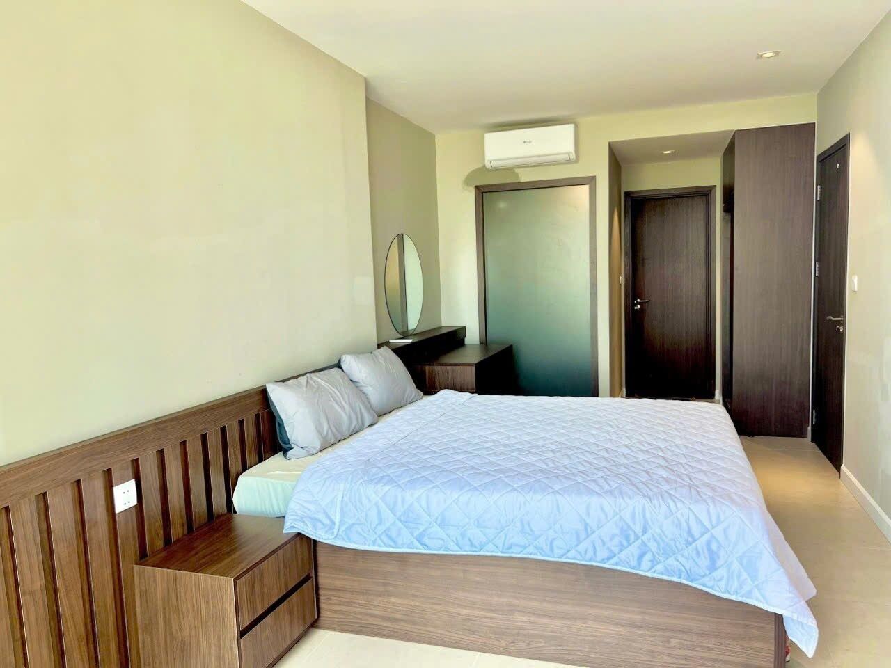 A bedroom with a bed, a bedside table, a mirror, and a wardrobe.