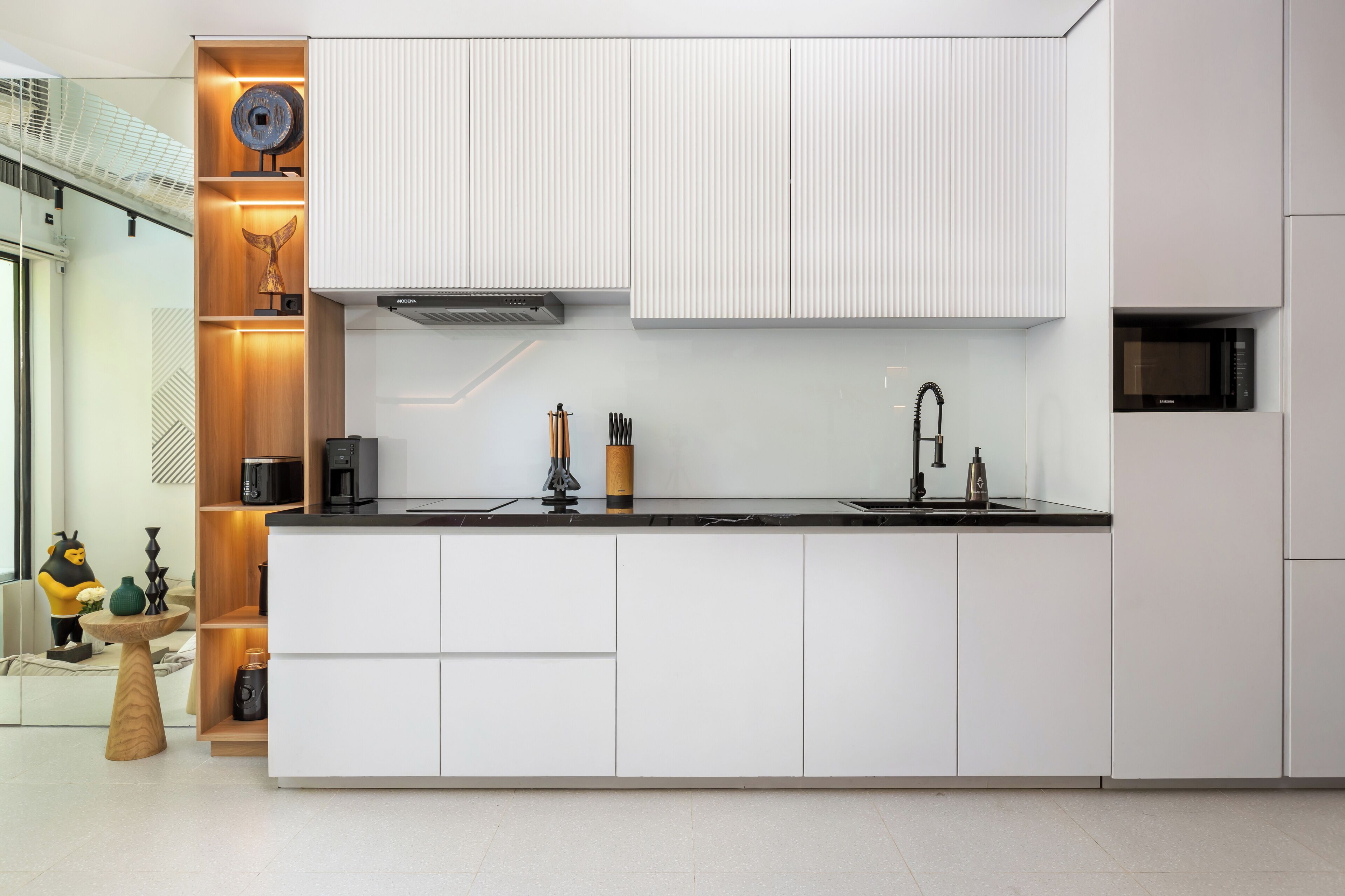 Een moderne keuken met witte kasten, een zwart aanrecht en een ingebouwde magnetron.