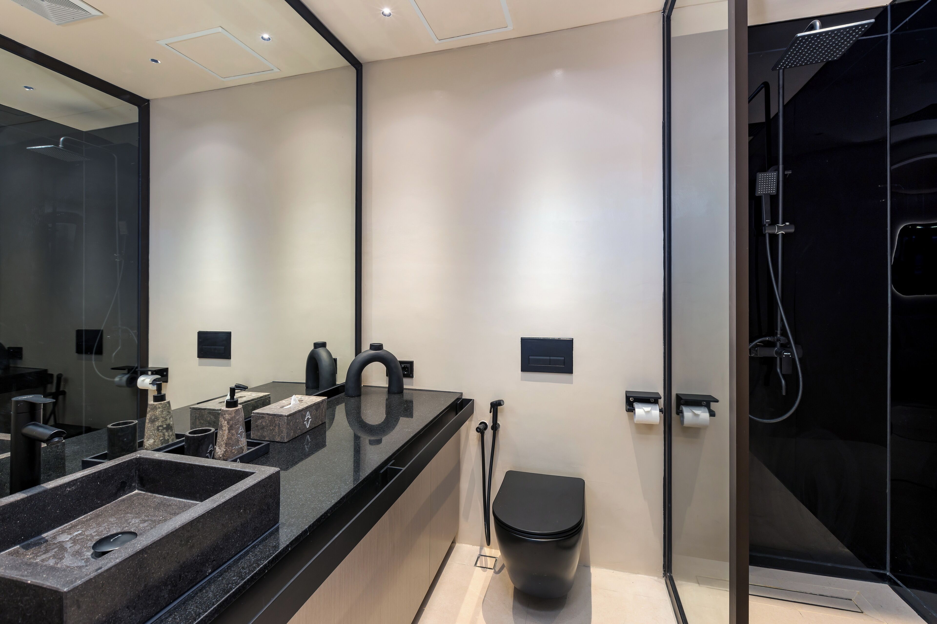 A modern bathroom with a black sink, a toilet, and a glass-enclosed shower.