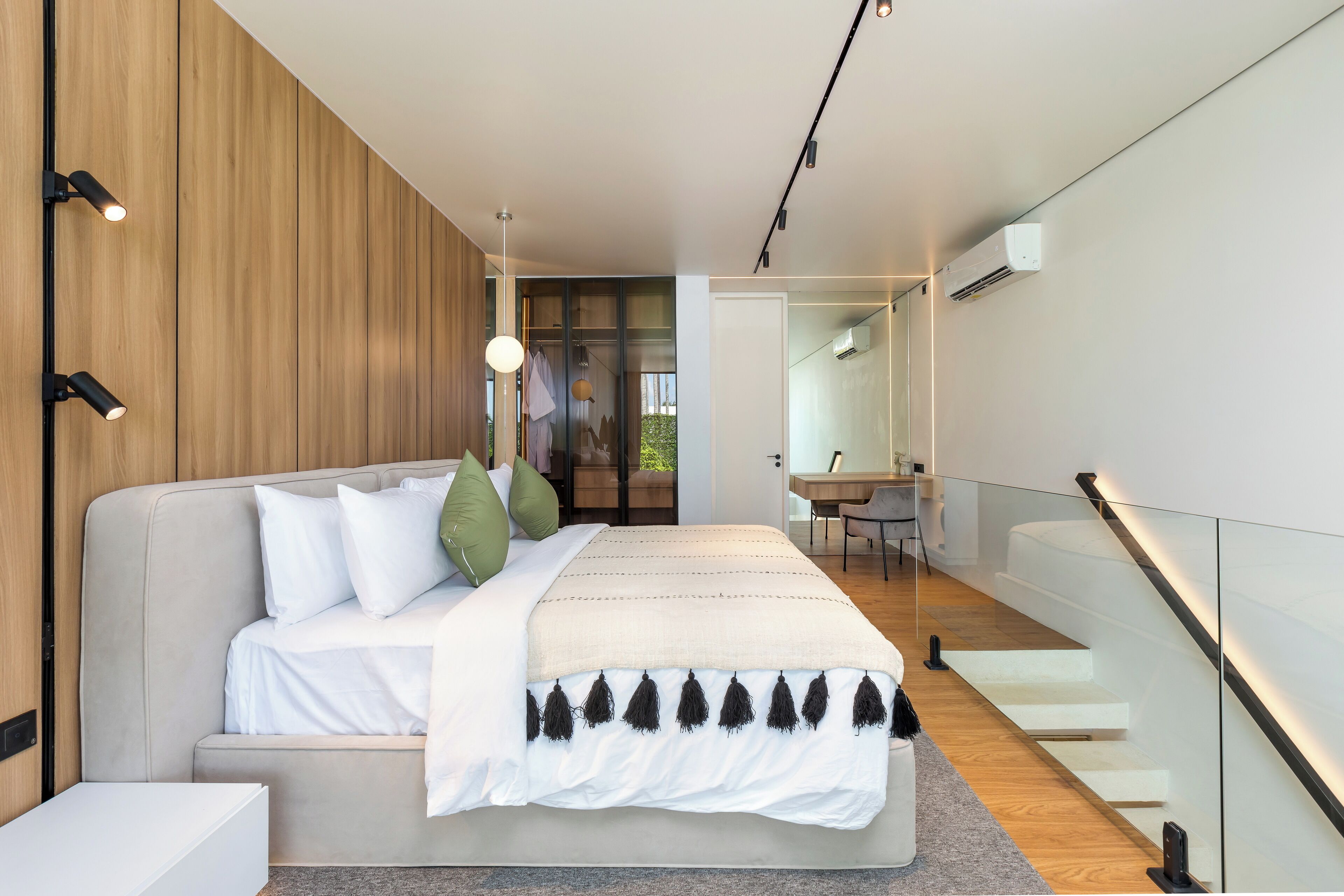 Un dormitorio moderno con una cama grande, un muro decorativo de madera y una escalera que sube a un nivel superior.