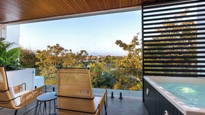 A modern outdoor seating area with a hot tub, overlooking a scenic view of trees and a distant mountain. - Alex Villas Complex N5 (Canggu)