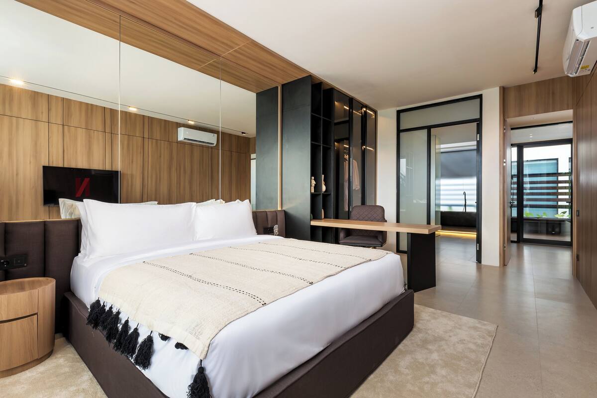 A modern bedroom with a large bed, built-in TV, and a desk with a chair.