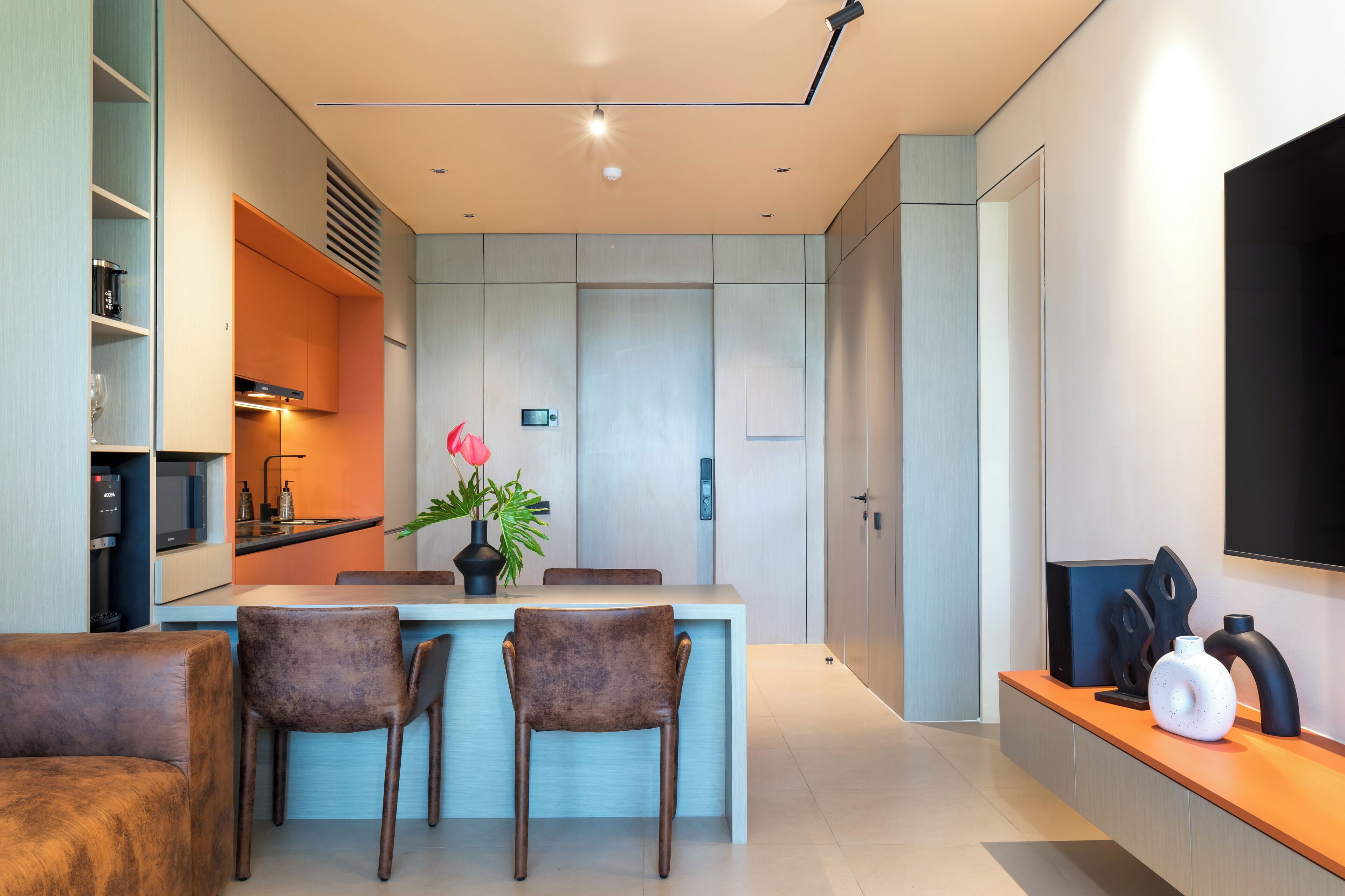 A modern kitchen with a central island, built-in appliances, and a dining area with chairs.