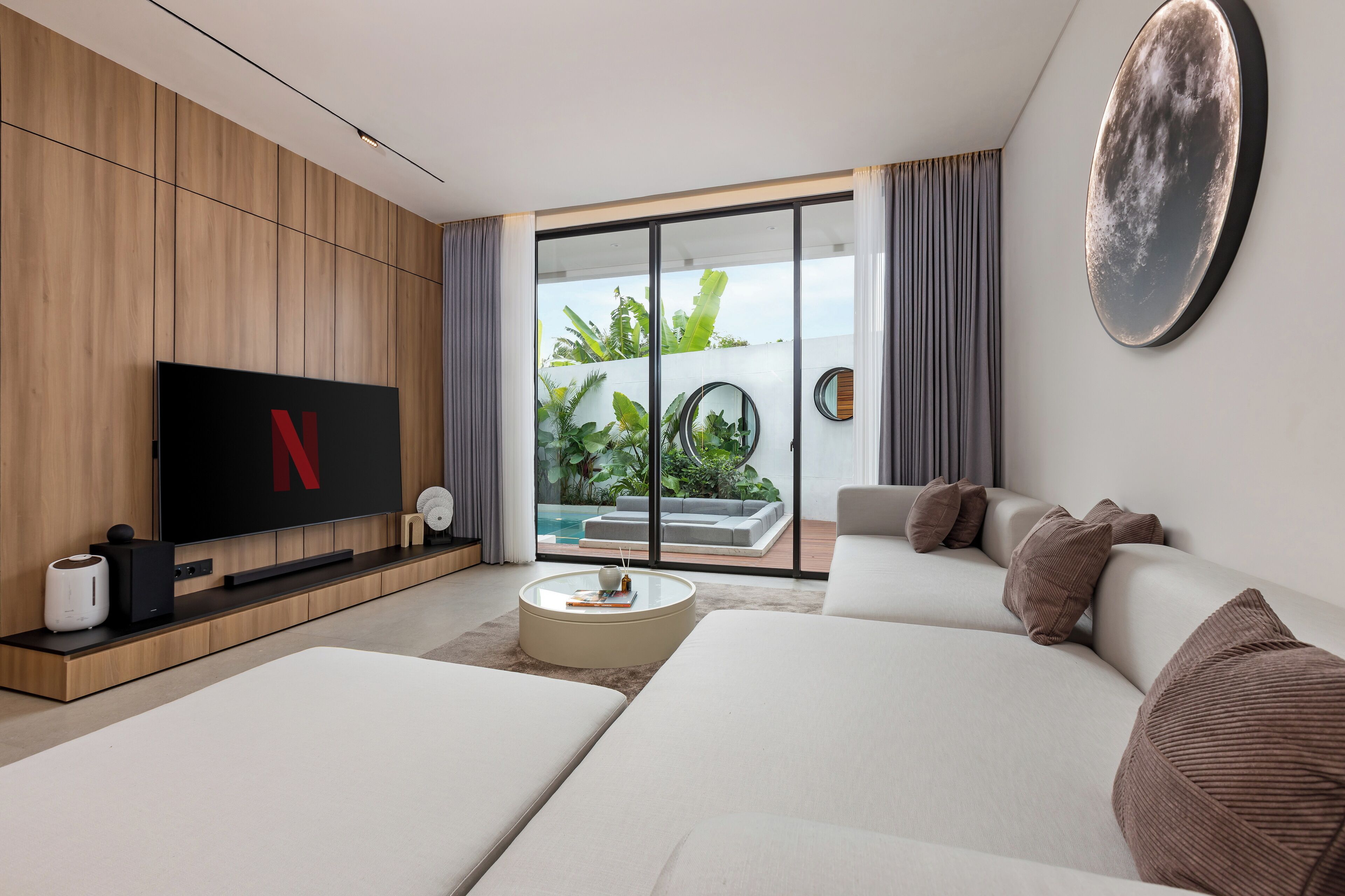 Een moderne woonkamer met een flatscreen televisie, een ronde salontafel en een bank.