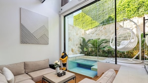 Una sala de estar moderna con un amplio ventanal, un sofá blanco, una mesa de centro y un sillón colgante.