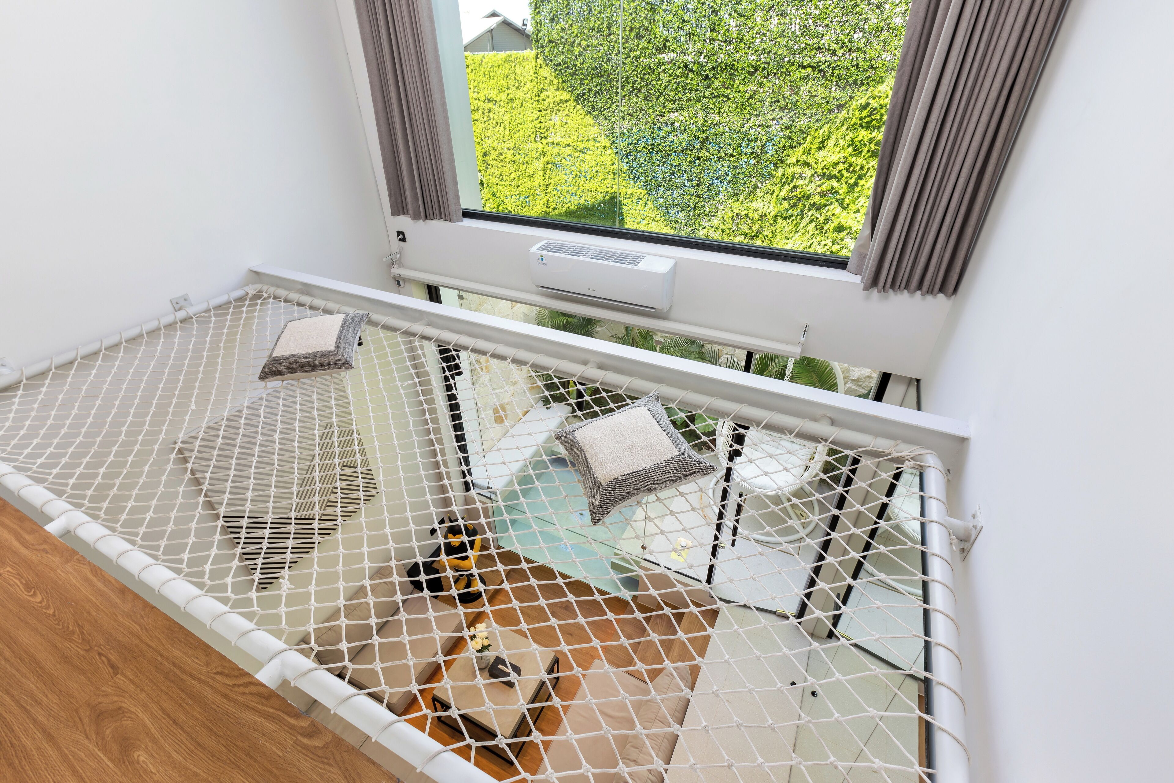 Habitación con ventana, aire acondicionado blanco y cama con mosquitera blanca.