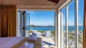Un dormitorio con un amplio ventanal que ofrece vistas panorámicas de un lago y colinas.