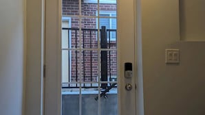 A white door with a glass panel, a keypad lock, and a small light above it. - Grapeview Lower Level Apartment (St. Catharines)