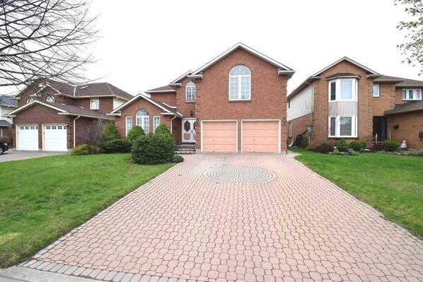 A suburban house with a brick facade, two attached garages, and a paved driveway.