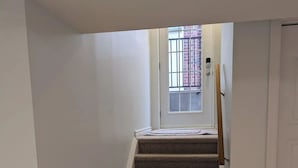 A carpeted staircase leading to a door with a window above it. - Grapeview Lower Level Apartment (St. Catharines)
