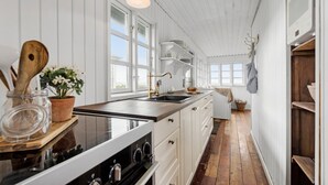 Eine Küche mit weißer Holzvertäfelung, einem großen Fenster und einem Holzboden.