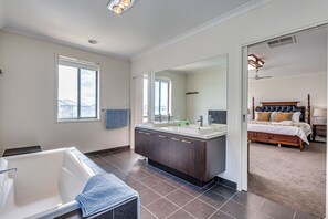A modern bathroom with a bathtub, vanity, and large mirror.
