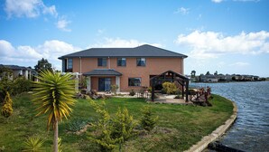 A two-story house with a patio and a small deck by a lake. - StayAU 5BR Lakefront Escape Point Cook (Point Cook)