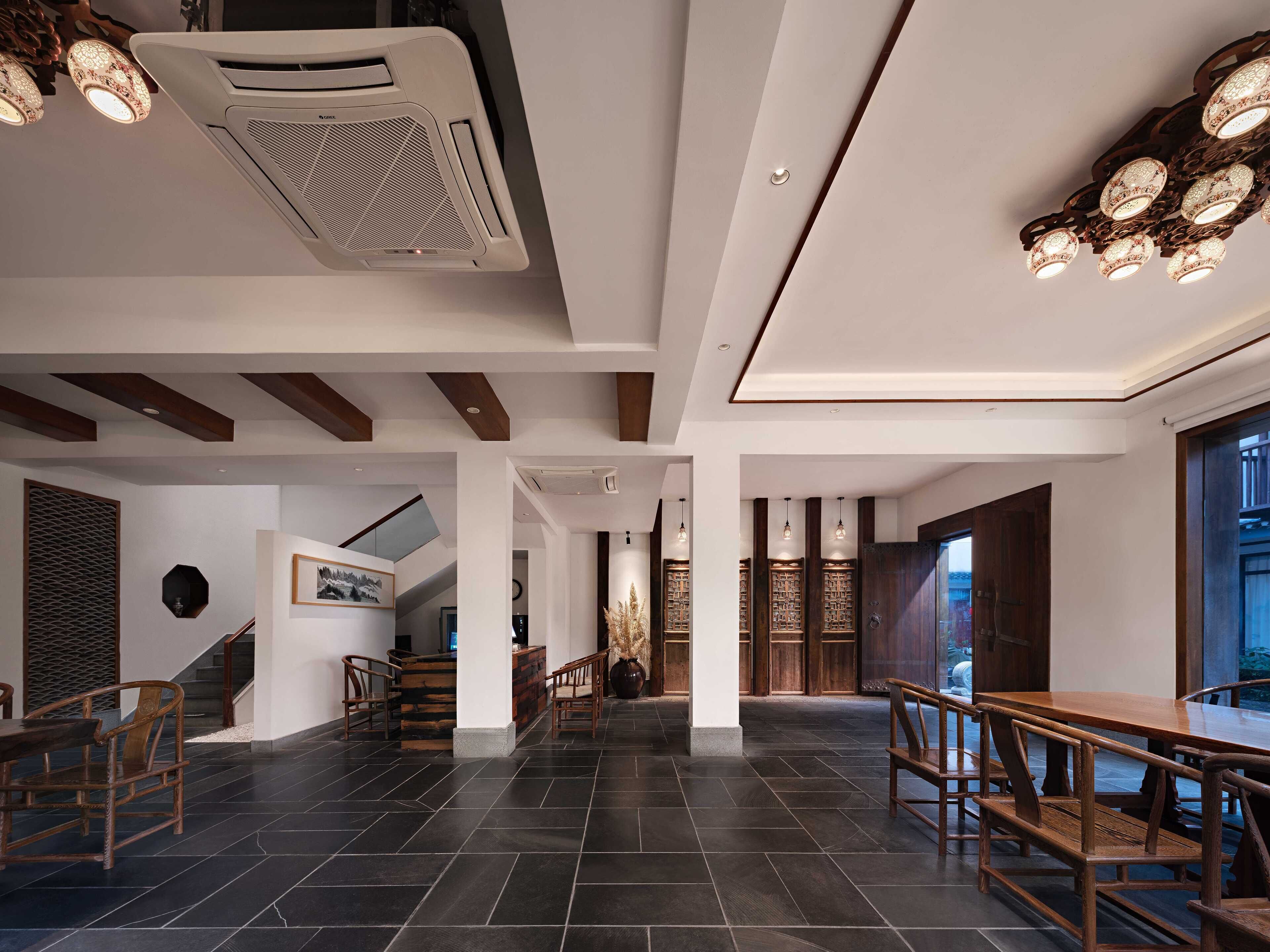 A spacious lobby with a staircase, wooden furniture, and a modern ceiling design.