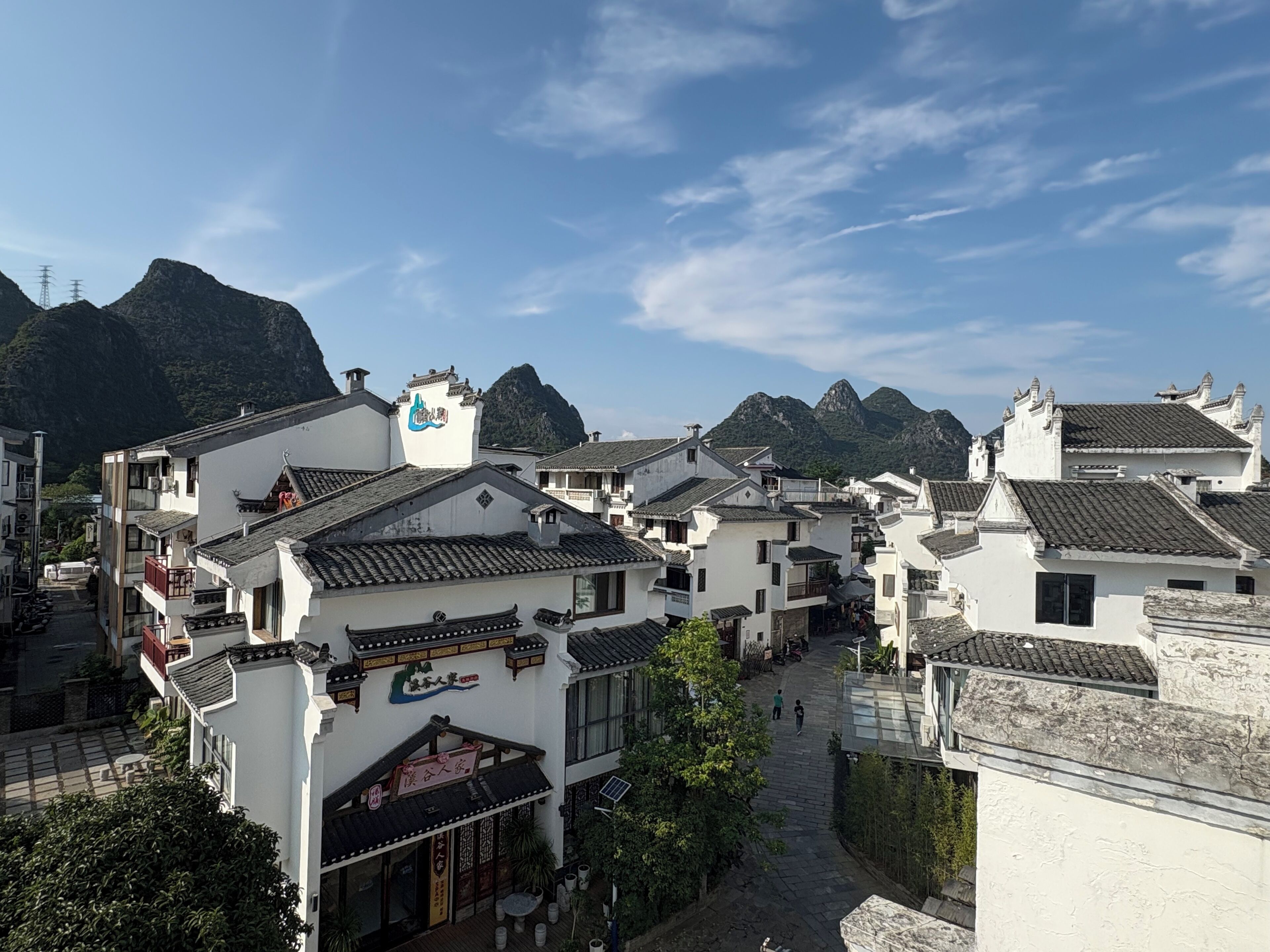 A traditional village with white buildings and tiled roofs, surrounded by mountains.