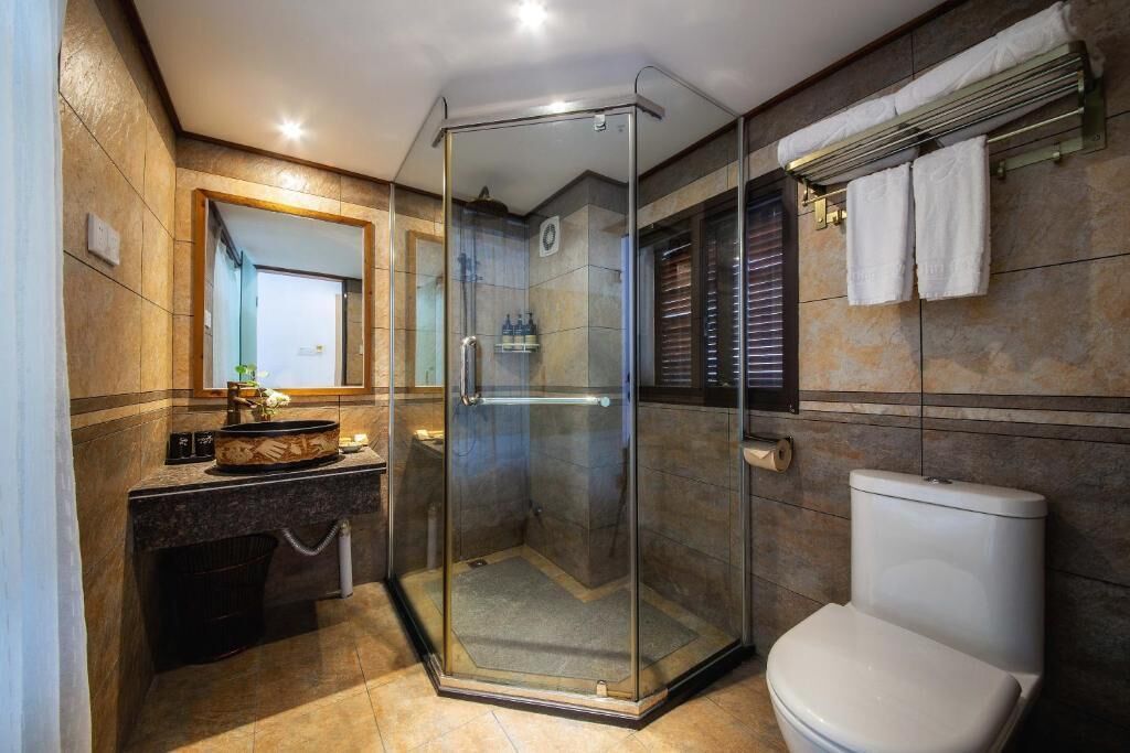 A modern bathroom with a glass-enclosed shower, a white toilet, and a vanity with a mirror and towel rack.