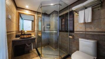 A modern bathroom with a glass-enclosed shower, a white toilet, and a vanity with a mirror and towel rack.