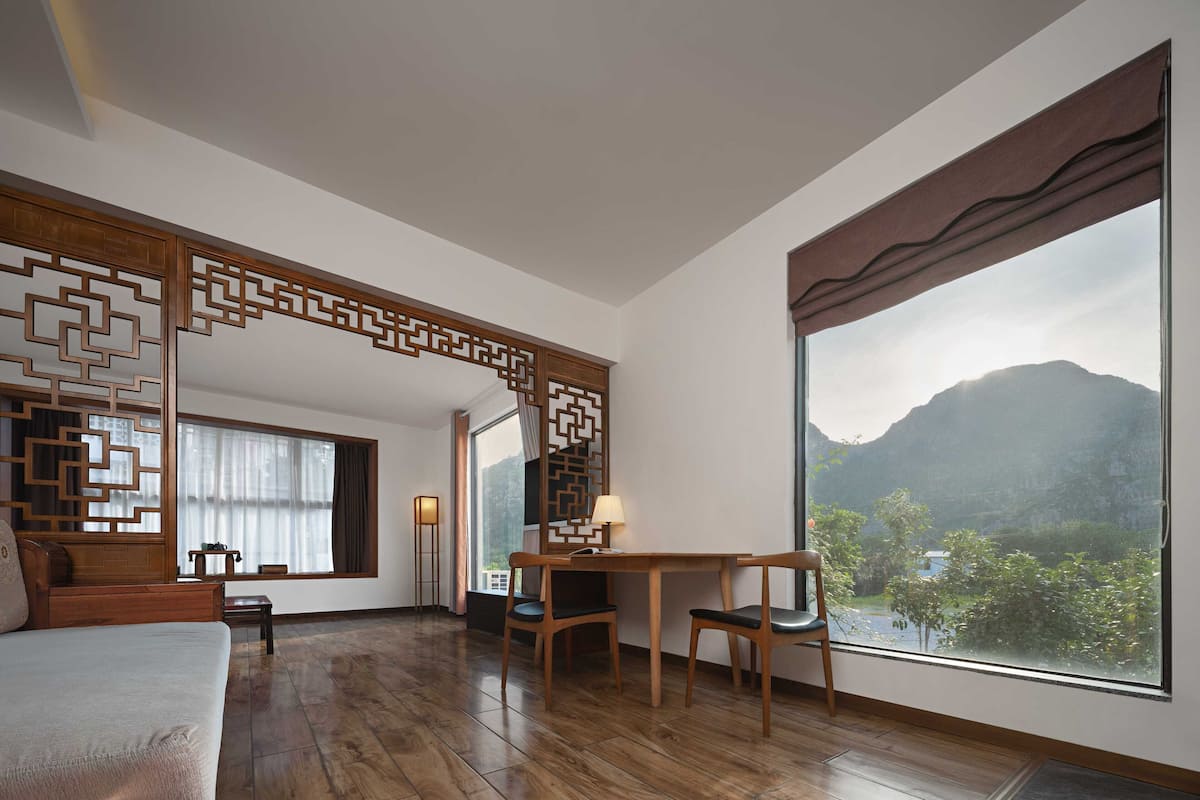 A room with a large window, wooden floor, and a traditional partition with geometric patterns.