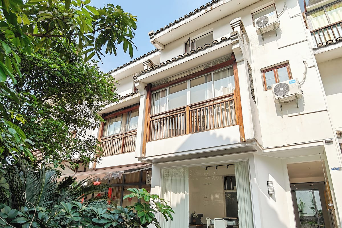 A two-story building with a balcony, large windows, and a small outdoor seating area.
