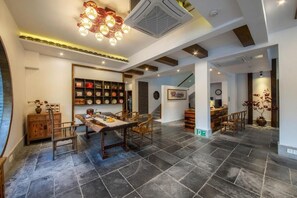 A spacious dining area with a wooden table and chairs, a decorative ceiling light, and a staircase leading to another level. - Serene Vale Inn Guilin (Guilin)