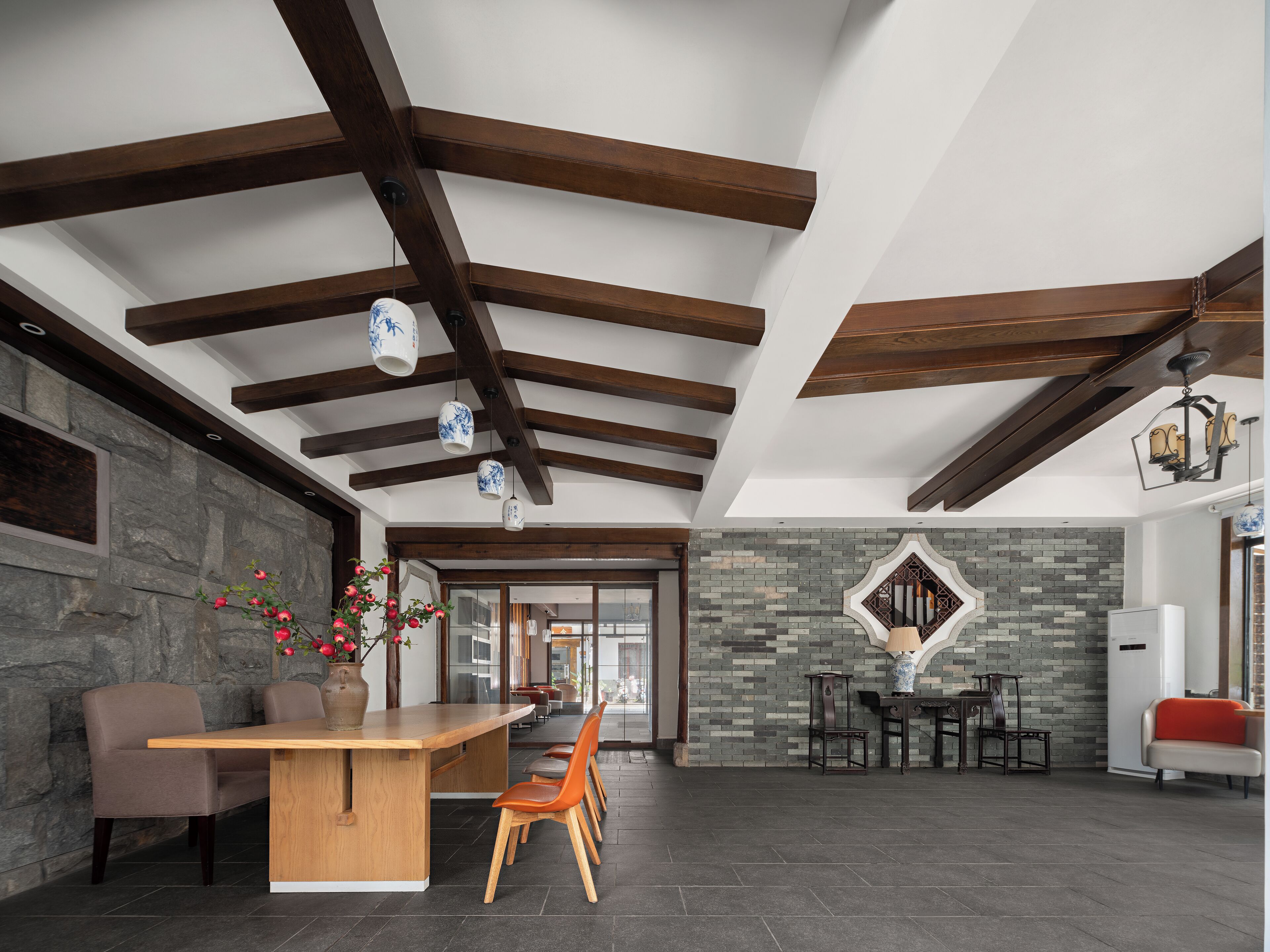 A spacious kitchen with a wooden ceiling, stone wall, and a large island with chairs.