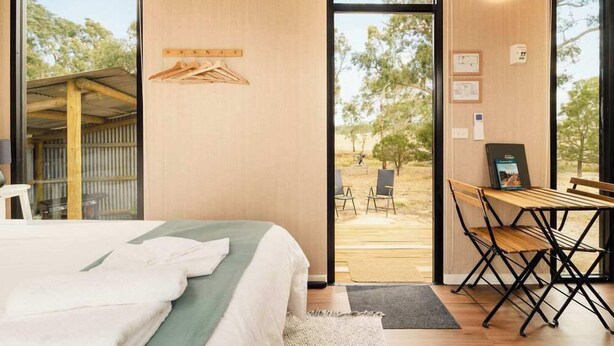 Habitación de hotel moderna con una cama, una mesa de madera y vistas al exterior.