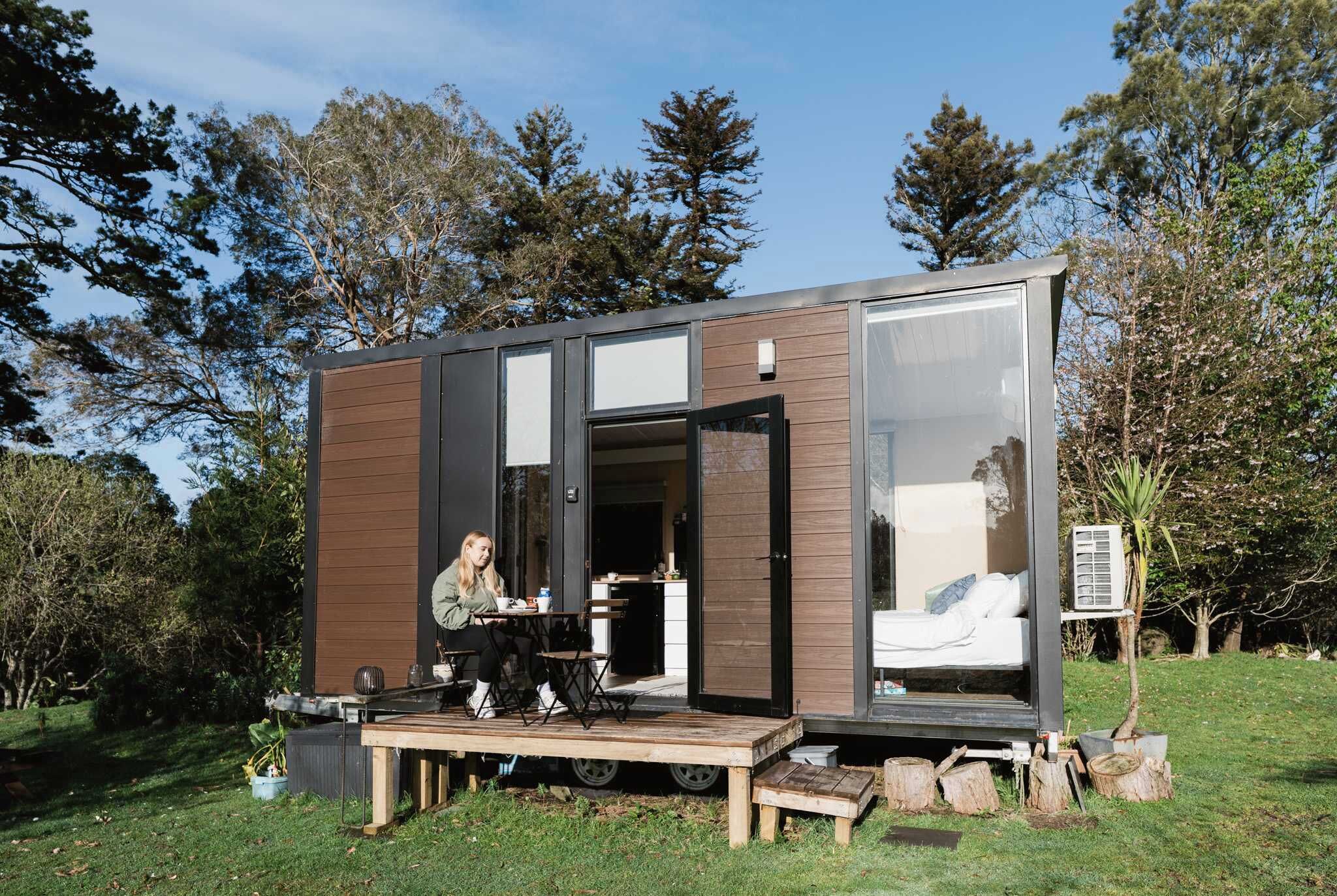 A modern, compact cabin with a deck, a bed, and a small kitchen area.