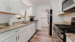 Una cucina moderna con mobili bianchi, piani di lavoro in granito, piano cottura in acciaio inossidabile e forno integrato.